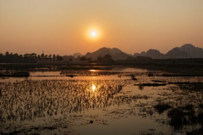 Un soleil voilé se reflète sur les étendues d'eau et rizières près de Tam Coc dans la province de Ninh Binh