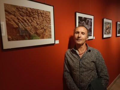 mon portrait de face adossé à un mur rouge devant une galerie de photos