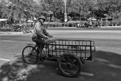 un vieil homme casqué chevauche un tricycle