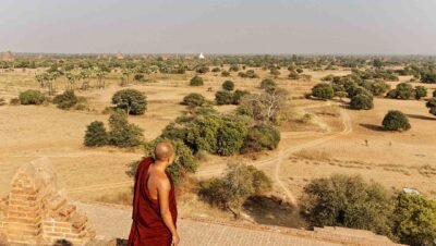 un moine bouddhiste vétu de rouge admire un paysage de la plaine de Bagan